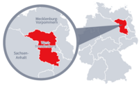 Diese Grafik zeigt eine Karte von Deutschland mit einer detaillierten Ansicht der Region West-Brandenburg. West-Brandenburg ist in Rot hervorgehoben und liegt im östlichen Teil Deutschlands. Ein Lupensymbol vergrößert diesen Bereich, um die Lage genauer darzustellen. 