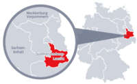 Diese Grafik zeigt eine Karte von Deutschland mit einer detaillierten Ansicht der Region Südbrandenburg-Lausitz. Südbrandenburg-Lausitz ist in Rot hervorgehoben und liegt im östlichen Teil Deutschlands. Ein Lupensymbol vergrößert diesen Bereich, um die Lage genauer darzustellen. 
